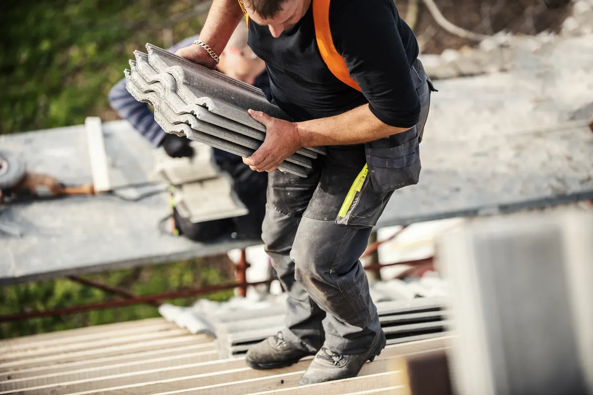 Roofer fixing new tiles on a pitched roof
